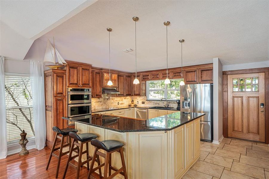 Kitchen featuring a multi-level island with dark countertops, wood cabinetry, and stainless steel appliances