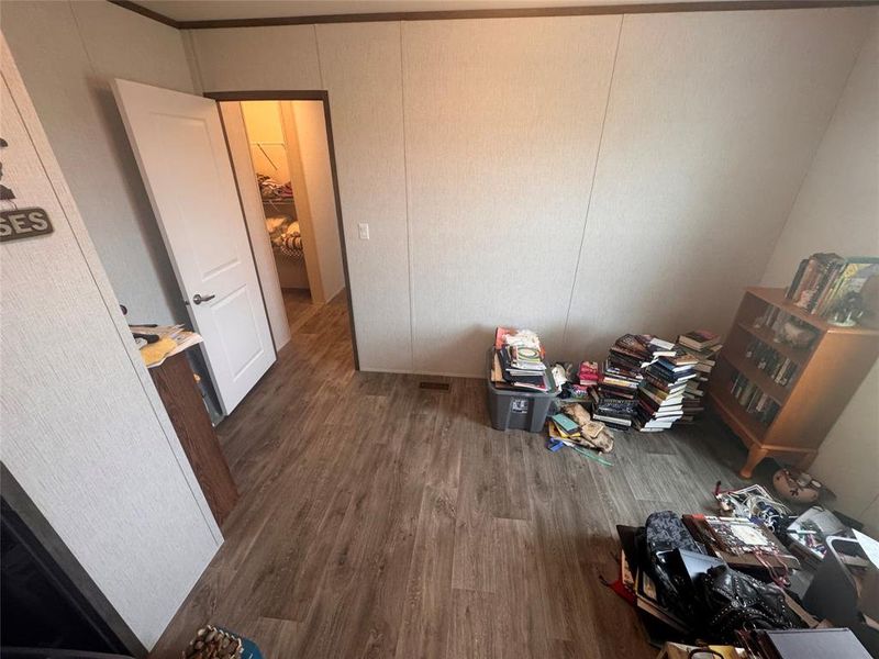 Unfurnished bedroom with a decorative wall and dark wood-style flooring Unfurnished bedroom with a decorative wall and dark wood-style flooring