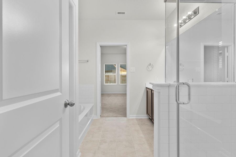 A view from the primary suite bathroom hallway highlights the dual vanity and generous counter space leading to the primary suite. This layout enhances functionality and flow, offering a private, spa-like atmosphere. A view from the primary suite bathroom hallway highlights the dual vanity and generous counter space leading to the primary suite. This layout enhances functionality and flow, offering a private, spa-like atmosphere.