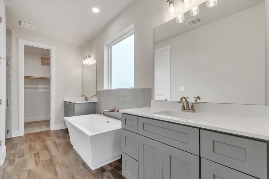 Unwind in this well-appointed primary bathroom, offering both a standalone soaking tub and a dedicated walk-in closet.