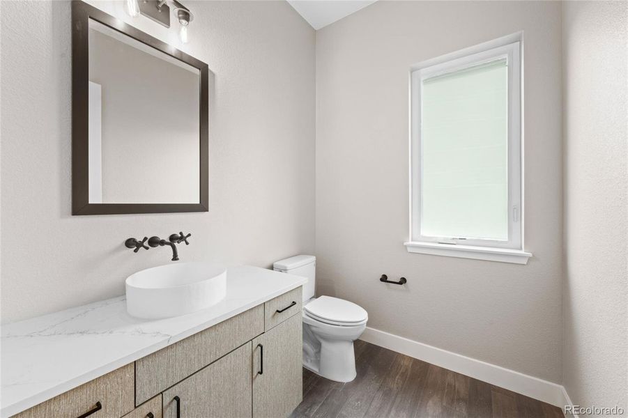 Main level powder room with quartz countertop, modern counter mount sink and fixtures.