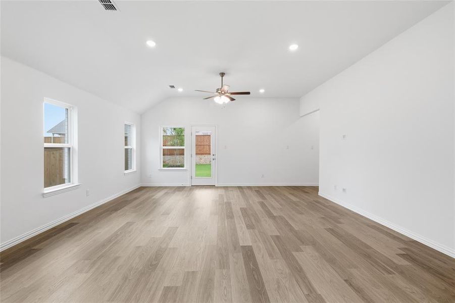Spacious living area featuring wood-finish flooring, vaulted ceiling, recessed lighting, and a ceiling fan
