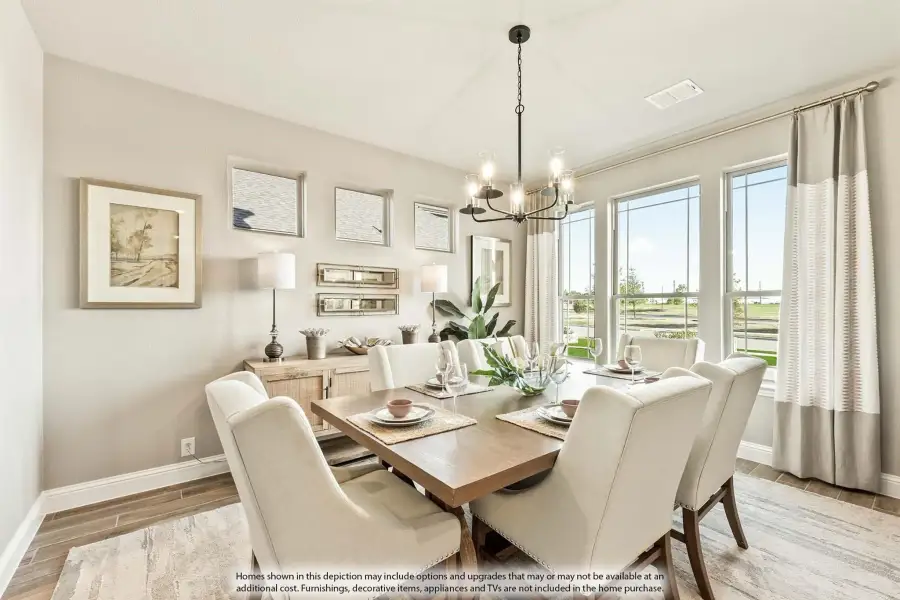 Dining room with wood table, white upholstered chairs, chandelier, and large windows with natural light