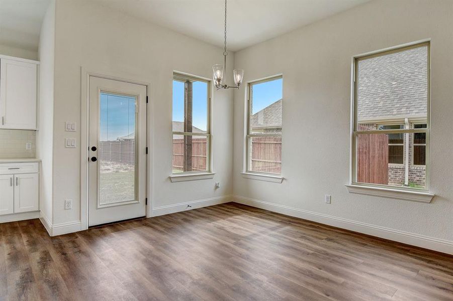 Unfurnished dining area with an inviting chandelier, a wealth of natural light, and dark wood-type flooring