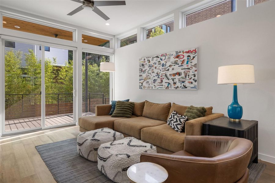 Living room with wood-type flooring, a high ceiling, ceiling fan, and recessed lighting