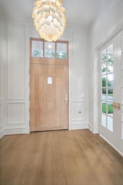 The Foyer shows the Custom Wood Entry door together with the the Visual Comfort Chandelier, Wood Paneled Walls with glossy finish, and the 9.5" white oak flooring.