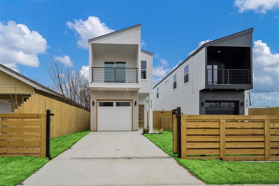 Contemporary house with a garage, a front yard, and a balcony