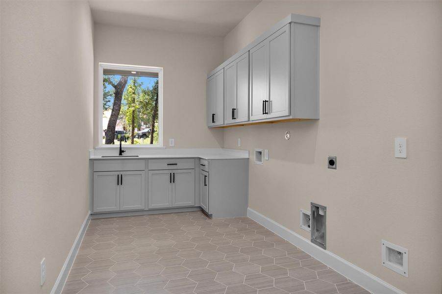 This well-equipped utility room features hexagon tile flooring, upper and lower cabinetry, a built-in sink and is prepped with plumbing and electrical for a full-size refrigerator.