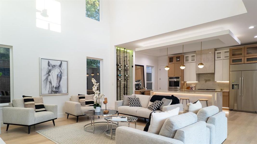 Living area featuring light wood-style flooring, a high ceiling, and plenty of natural light