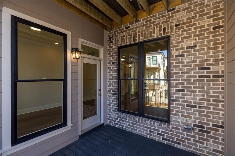 View of exterior entry with brick siding and a wooden deck