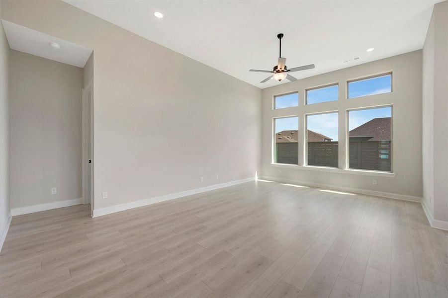 Spacious room featuring wood-finish flooring, high ceilings with recessed lighting, and a contemporary ceiling fan