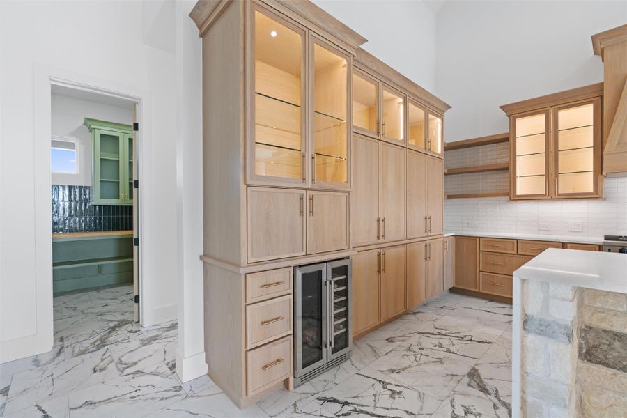 Bar area with open shelves, glass insert cabinets, light marble finish flooring, and backsplash