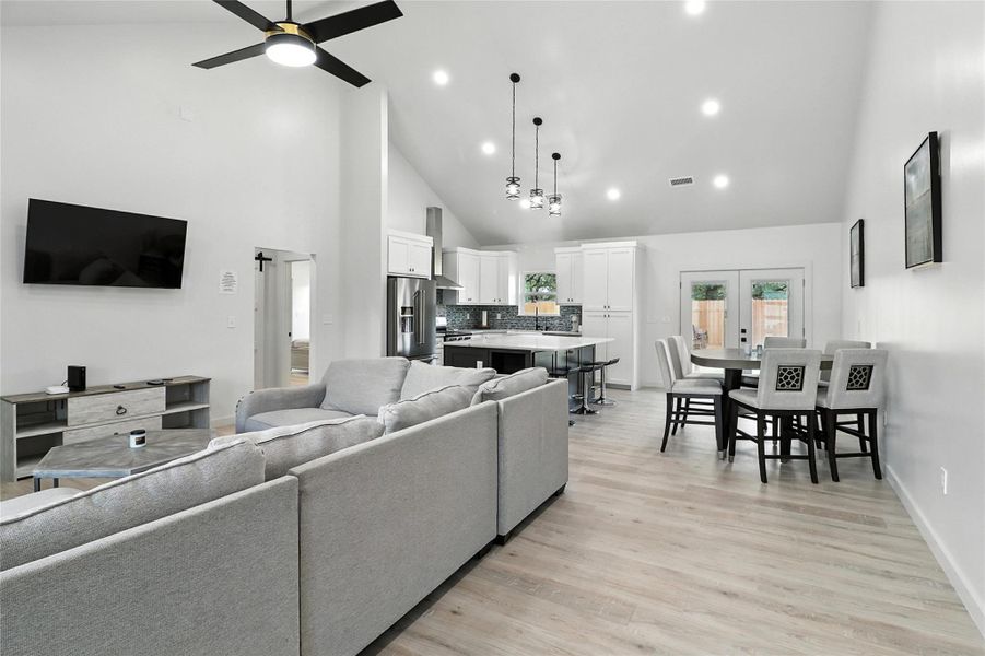 Living area featuring high vaulted ceiling, light wood finished floors, a ceiling fan, and recessed lighting