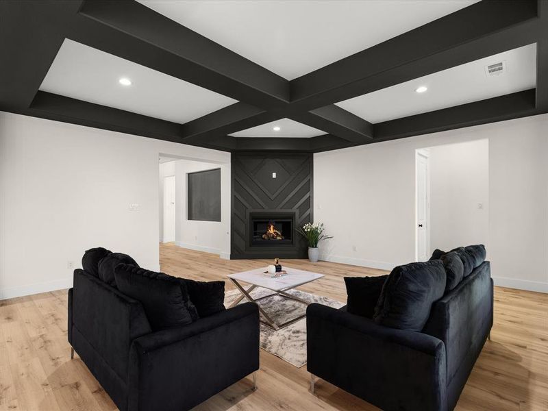 Living room with light wood-style floors, a fireplace, coffered ceiling, and recessed lighting