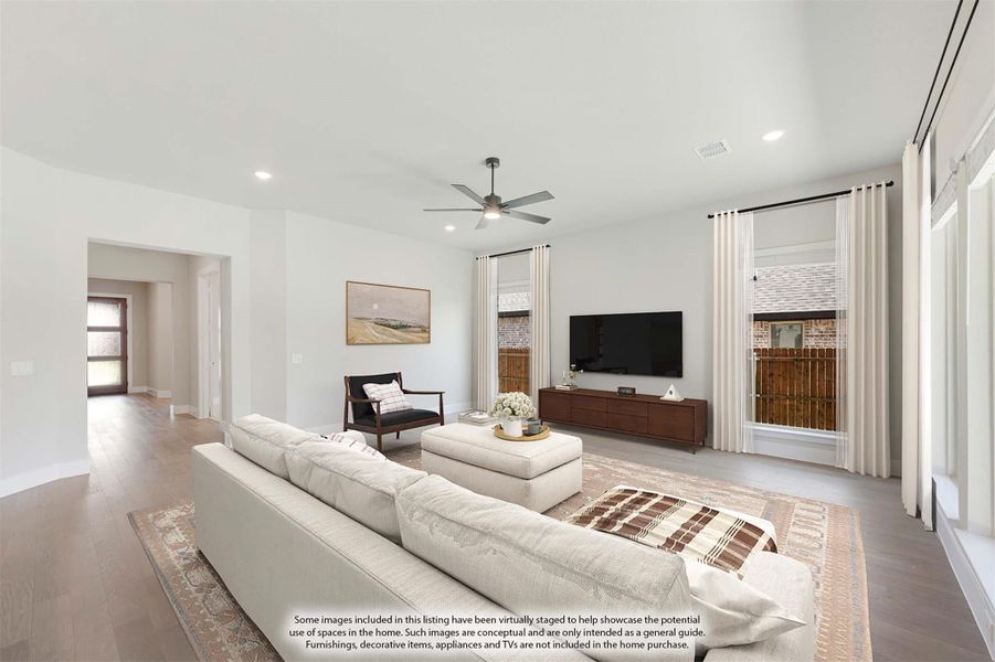 Bright living room with white sectional sofa, ceiling fan, hardwood floors, and large windows with curtains