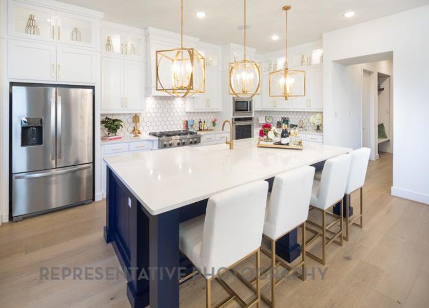 Kitchen with white cabinetry, backsplash, a chandelier, and appliances with stainless steel finishes Kitchen with white cabinetry, backsplash, a chandelier, and appliances with stainless steel finishes