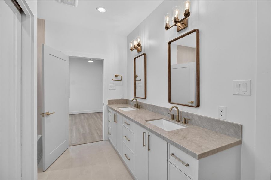Designed with both style and functionality in mind, this shared full bathroom features dual vanities with double sinks, designer finishes, and ample counter space, providing comfort and convenience for family members and guests alike. Designed with both style and functionality in mind, this shared full bathroom features dual vanities with double sinks, designer finishes, and ample counter space, providing comfort and convenience for family members and guests alike.
