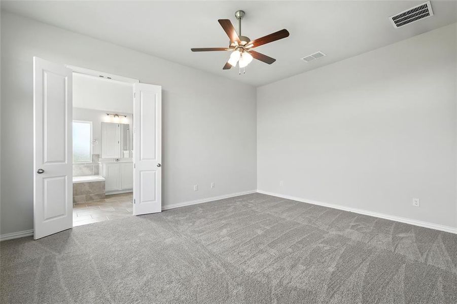 Unfurnished bedroom with a ceiling fan, light colored carpet, and ensuite bath Unfurnished bedroom with a ceiling fan, light colored carpet, and ensuite bath