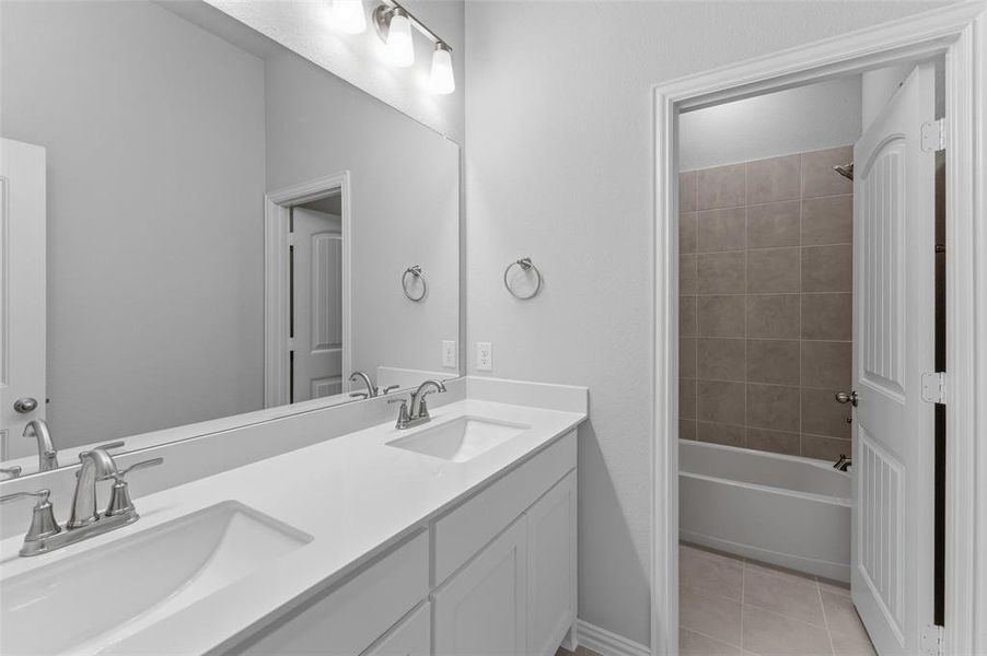 Bathroom featuring a double vanity with white countertops and two sinks, brushed nickel faucets, and a large mirror