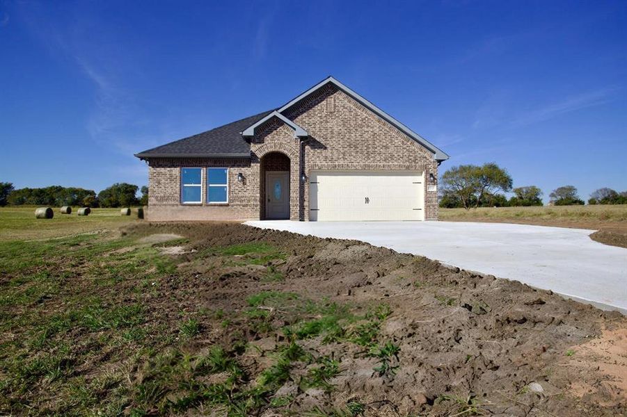View of front of house with brick siding, driveway, and a garage