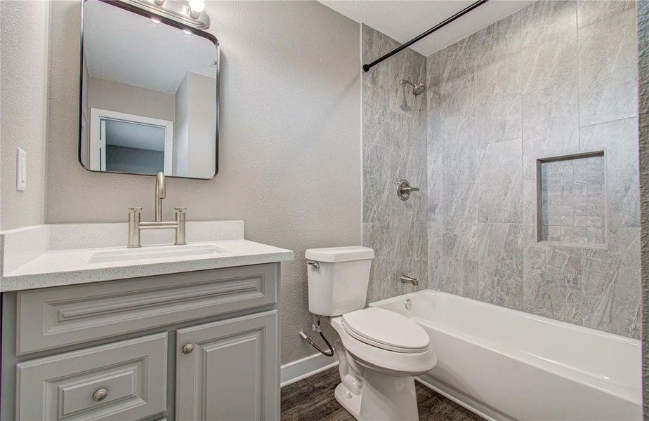 Primary bathroom with a modern vanity, framed mirror, and tiled tub-and-shower combination.