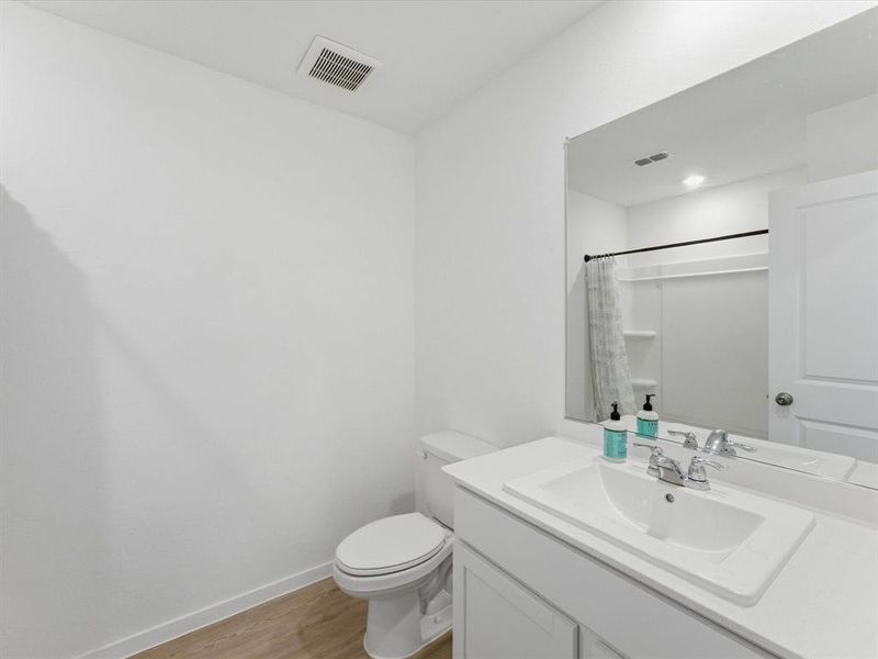 Bathroom featuring a single vanity with an integrated sink, polished chrome faucet, and a wall-mounted mirror