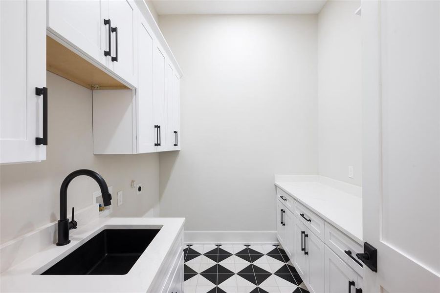 Clothes washing area featuring sink, cabinets, and light tile patterned flooring