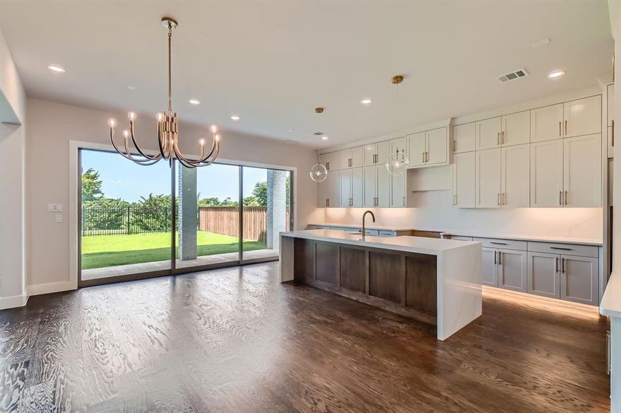 Kitchen featuring a chandelier, an island with sink, dark wood-style floors, and recessed lighting Kitchen featuring a chandelier, an island with sink, dark wood-style floors, and recessed lighting