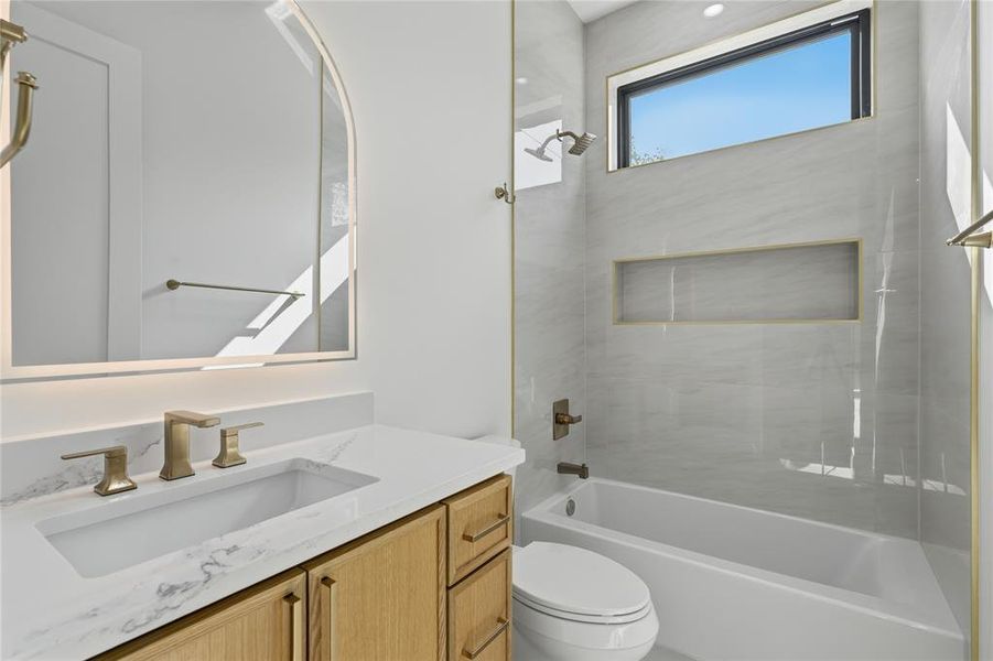 Bathroom featuring a light wood vanity with a white countertop, an undermount sink, and brass fixtures Bathroom featuring a light wood vanity with a white countertop, an undermount sink, and brass fixtures