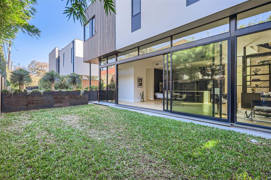 A modern exterior facade blends natural wood and white siding, featuring extensive sliding glass doors opening to a lush, green yard. A modern exterior facade blends natural wood and white siding, featuring extensive sliding glass doors opening to a lush, green yard.