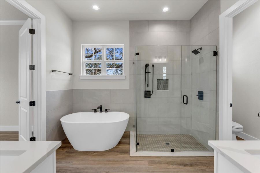 Full bathroom featuring vanity, a shower stall, light wood-style flooring, a soaking tub, and tile walls