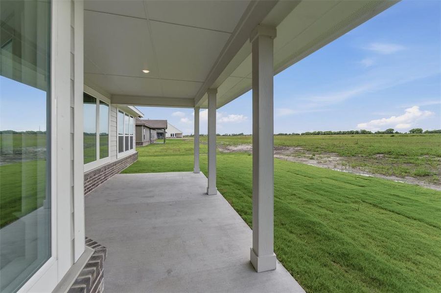 Covered concrete patio with white columns and a recessed light fixture Covered concrete patio with white columns and a recessed light fixture