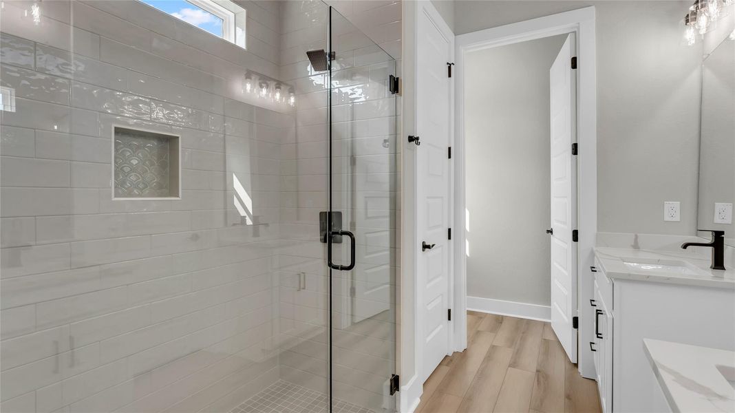 Bathroom with double vanity, a shower stall, and light wood finished floors