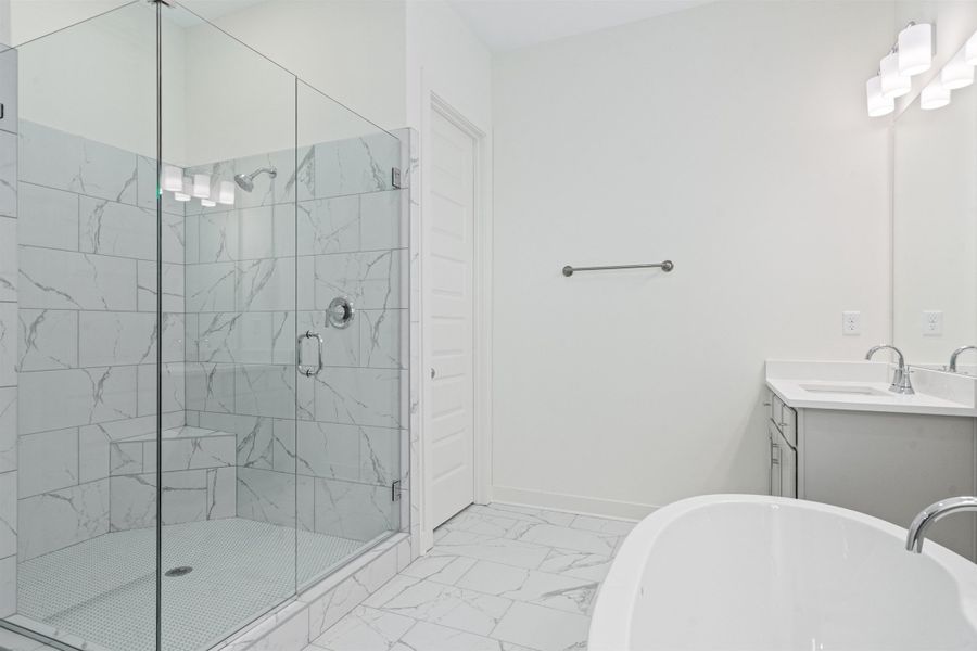 Bathroom featuring vanity, a soaking tub, a marble finish shower, and light marble finish floors