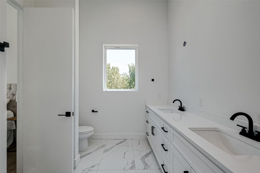Bathed in natural light, this spacious en-suite bathroom features a stunning double vanity, private toilet area, and serene treetop views.