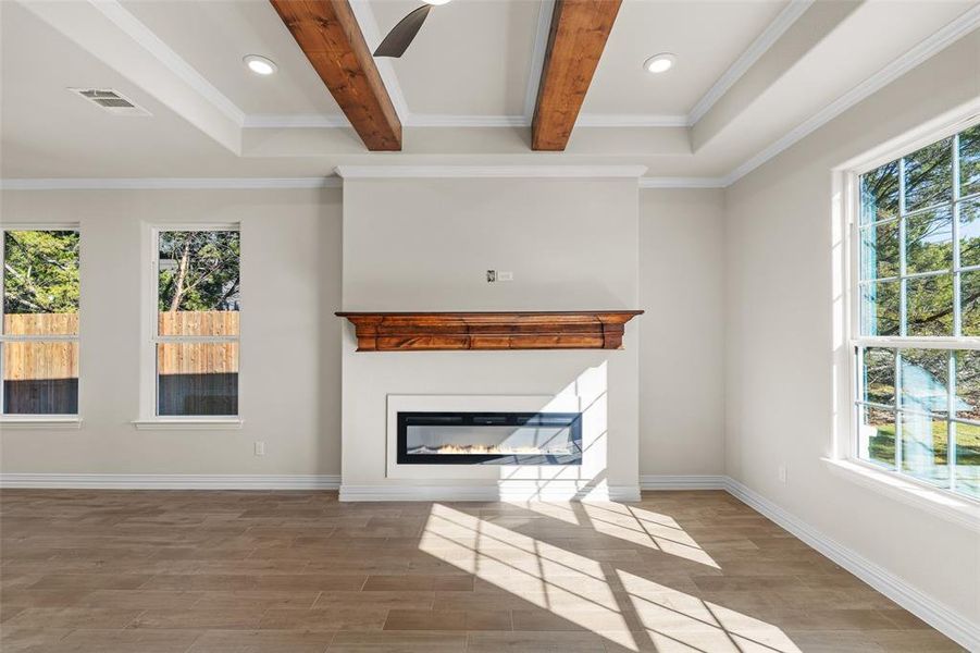 Unfurnished living room featuring beamed ceiling, hardwood / wood-style flooring, and a wealth of natural light