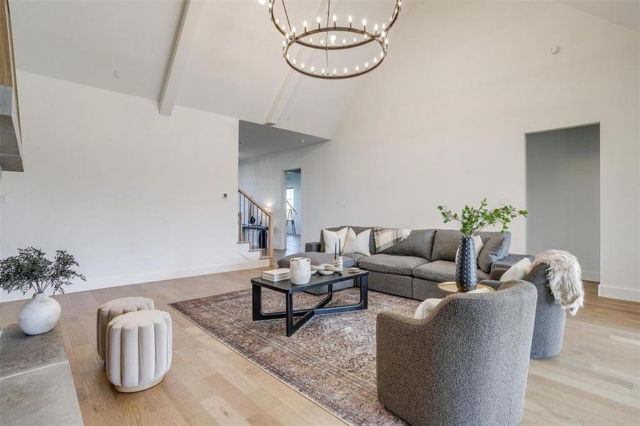 Living room featuring light hardwood / wood-style floors, high vaulted ceiling, beamed ceiling, and a chandelier