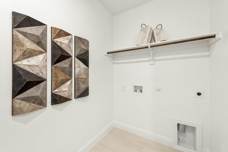 Laundry room with wall-mounted shelf, hanging rod, washer hookups, and decorative wood panel wall art