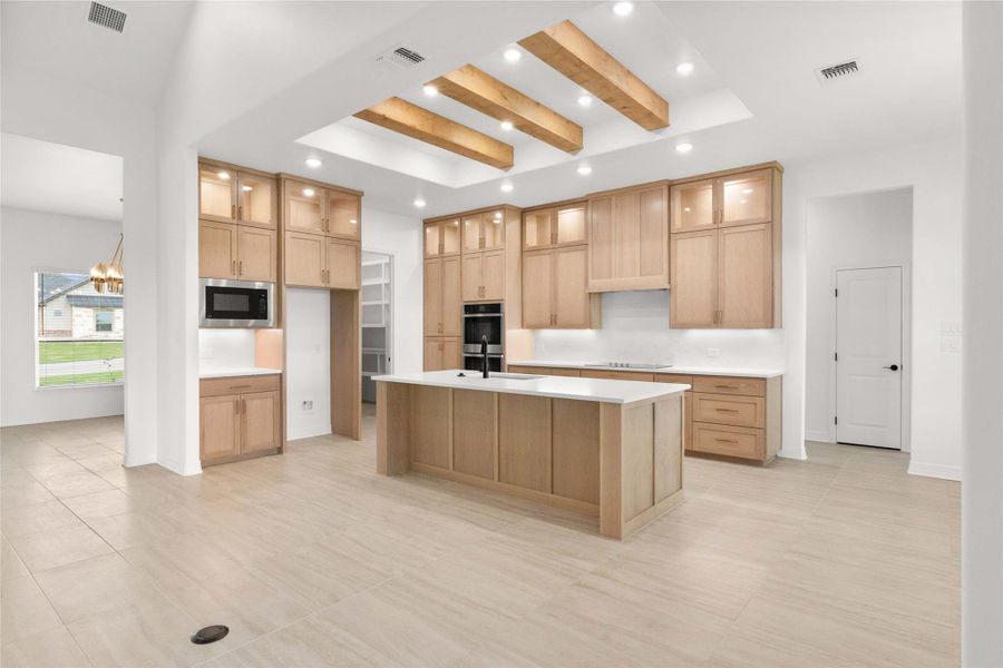 A well-appointed kitchen showcasing light-toned cabinetry, an island with a breakfast bar, and recessed lighting with exposed beam accents. A well-appointed kitchen showcasing light-toned cabinetry, an island with a breakfast bar, and recessed lighting with exposed beam accents.