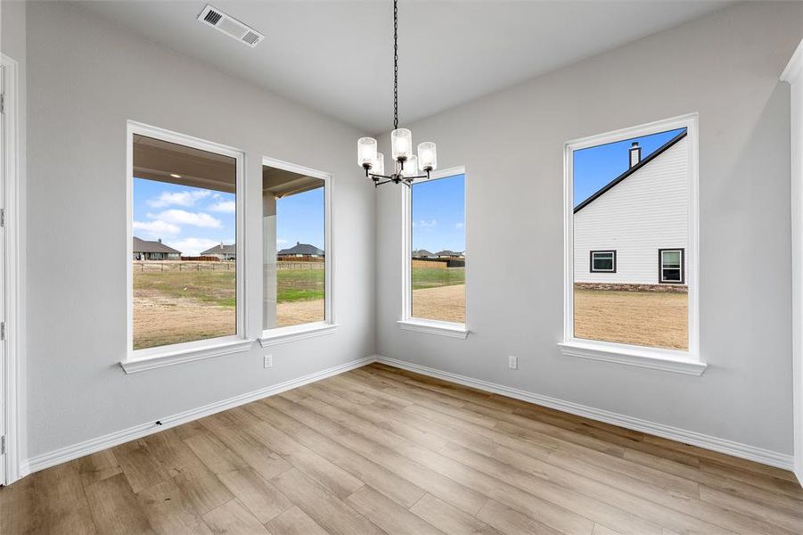 Unfurnished dining area with a chandelier, light wood finished floors, and healthy amount of natural light Unfurnished dining area with a chandelier, light wood finished floors, and healthy amount of natural light