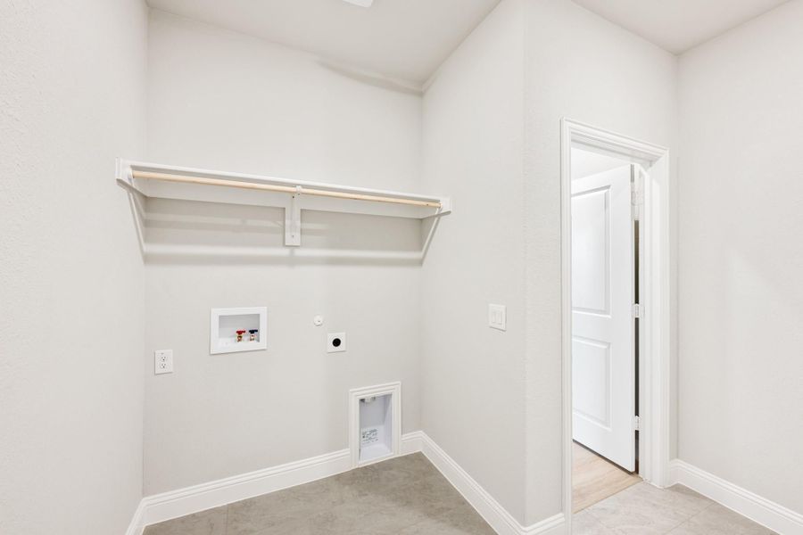 Empty laundry room with washer and dryer hookups, wall shelf, and open white door Empty laundry room with washer and dryer hookups, wall shelf, and open white door