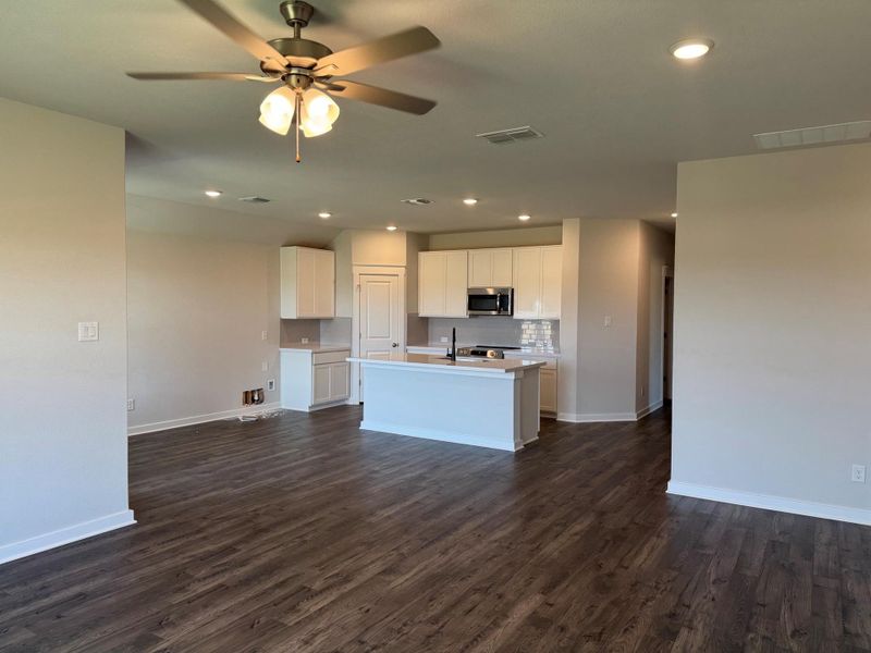 Kitchen featuring stainless steel microwave, open floor plan, dark wood-style floors, a center island with sink, and recessed lighting Kitchen featuring stainless steel microwave, open floor plan, dark wood-style floors, a center island with sink, and recessed lighting