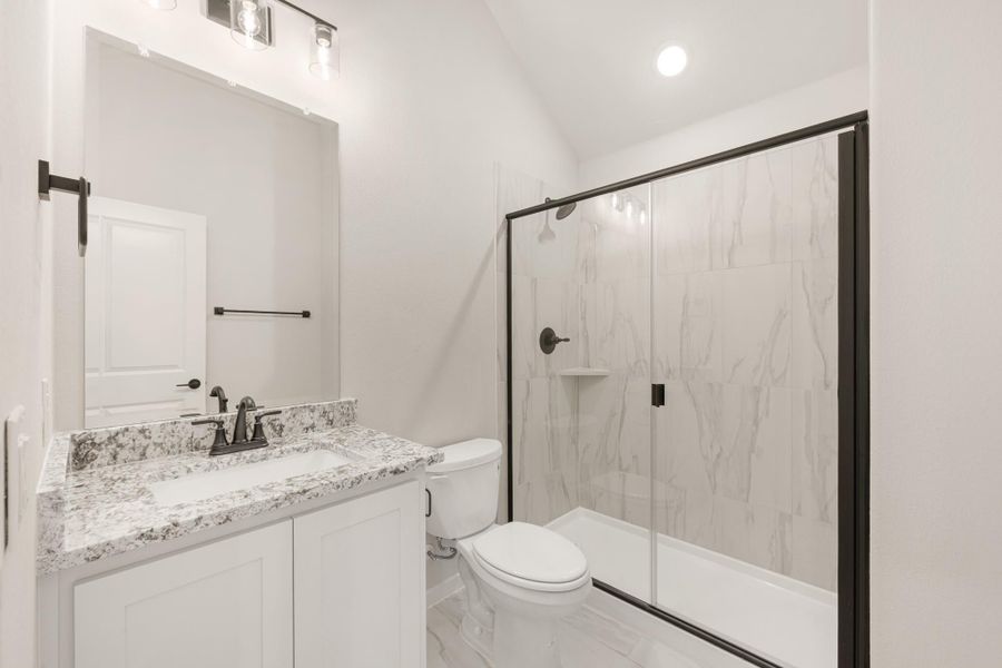 Bathroom with granite vanity, white cabinets, and glass-enclosed shower with marble tile walls