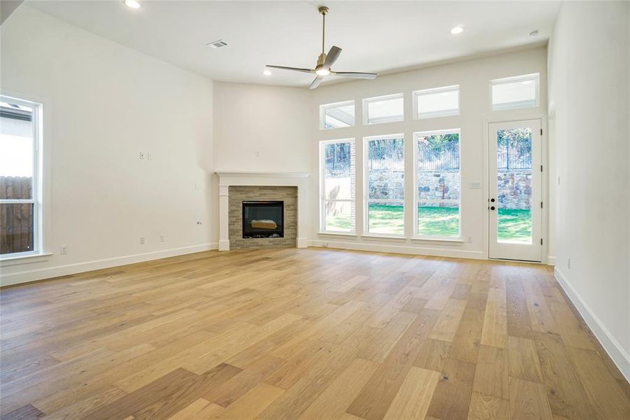 Unfurnished living room featuring light wood-style floors, a glass covered fireplace, recessed lighting, and ceiling fan