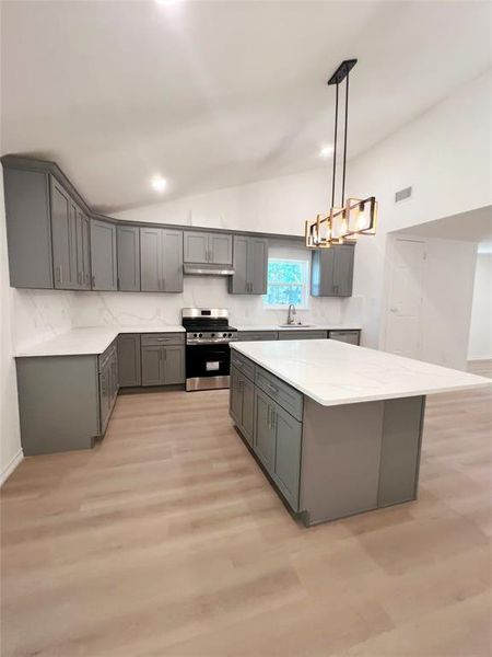 Modern kitchen featuring gray shaker-style cabinetry, white countertops, and light wood-finish flooring