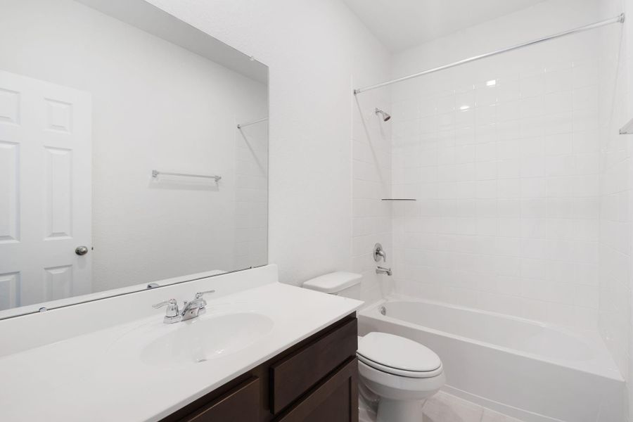 The secondary bath features tile flooring, white cabinetry and light countertops and a shower/tub combo. Perfect for accommodating any visiting family and friends.