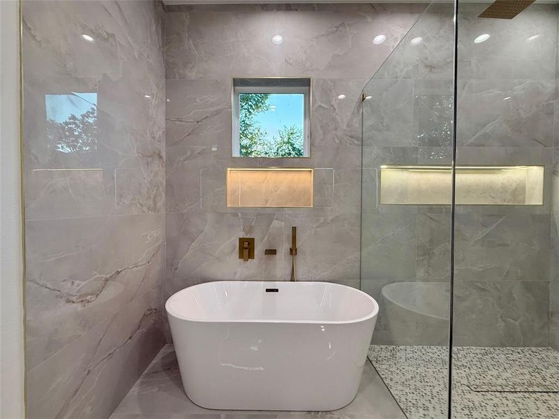Bathroom with a soaking tub, a marble finish shower, tile walls, and marble tiled floors