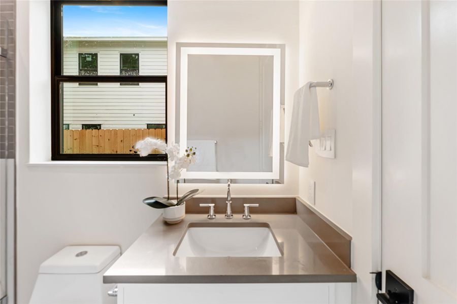 Large vanity mirror with built in LED lighting adds even more light to the luxurious full bathroom.