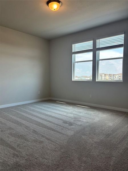 Carpeted spare room featuring baseboards