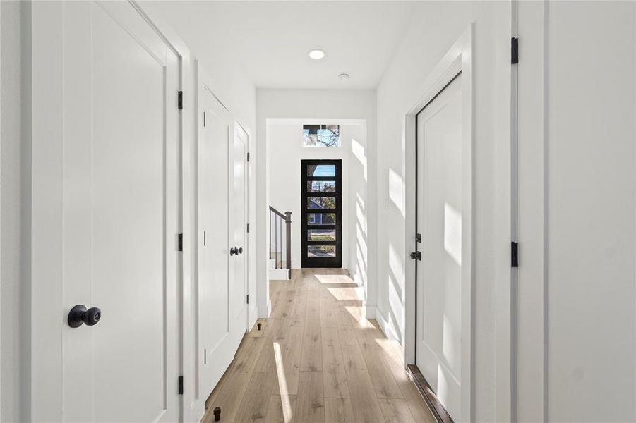 Hall with light wood finished floors and recessed lighting
